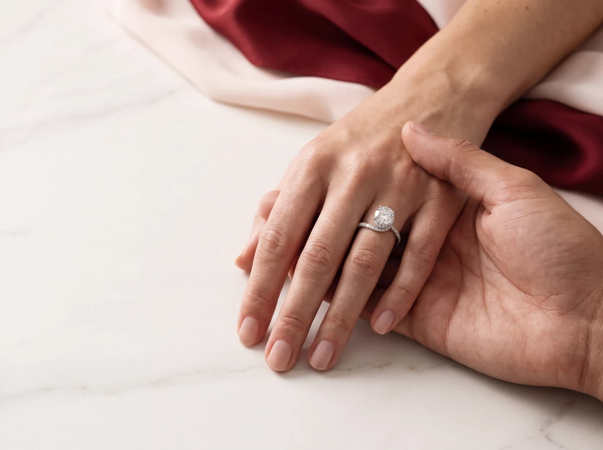 Two hands resting together, one wearing a DANHOV diamond engagement ring